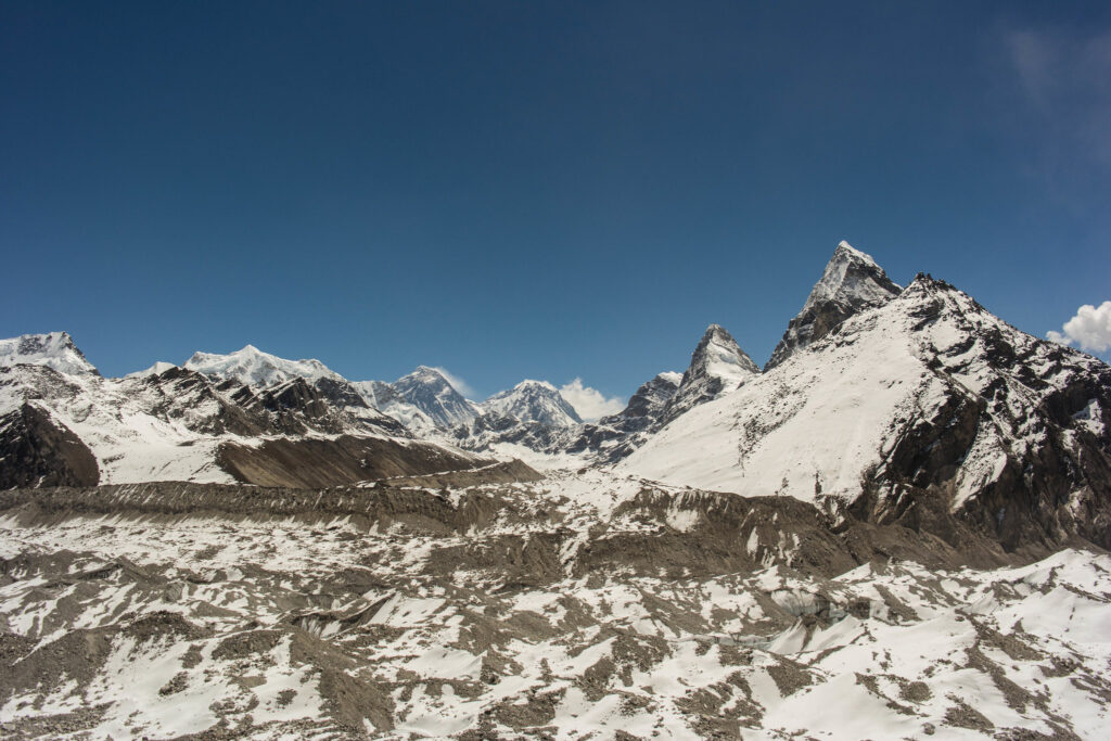 Snow-covered Himalayan peaks above glacier and rocky terrain