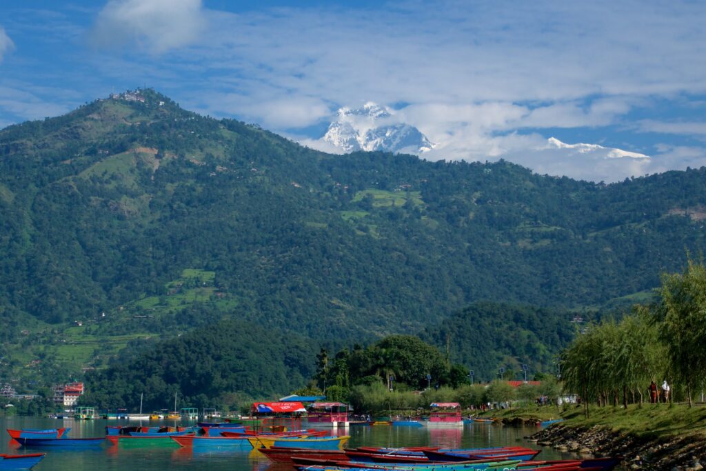 Women Travelers in Nepal at scenic lake with boats and mountains